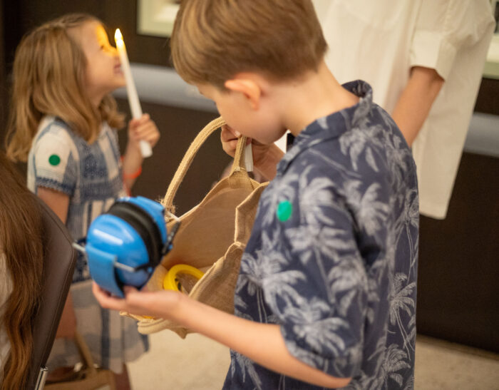 boy looking in bag holding ear defenders and girl in background with electric candle lit up